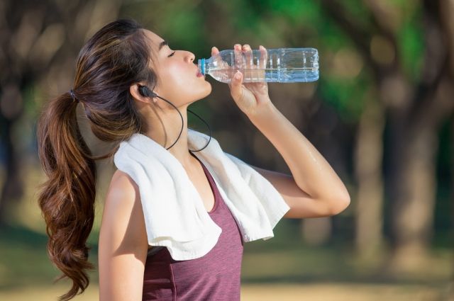 восточная девушка, спортсменка, пьёт из бутылки воду